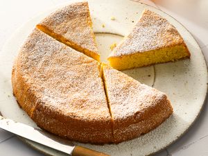 A sliced flourless lemon almond cake on a plate with a knife