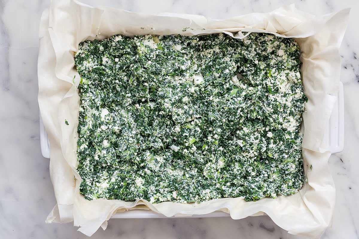 Phyllo lining a casserole dish filled with spinach and cheese for spanakopita a.k.a Greek Spinach Pie.