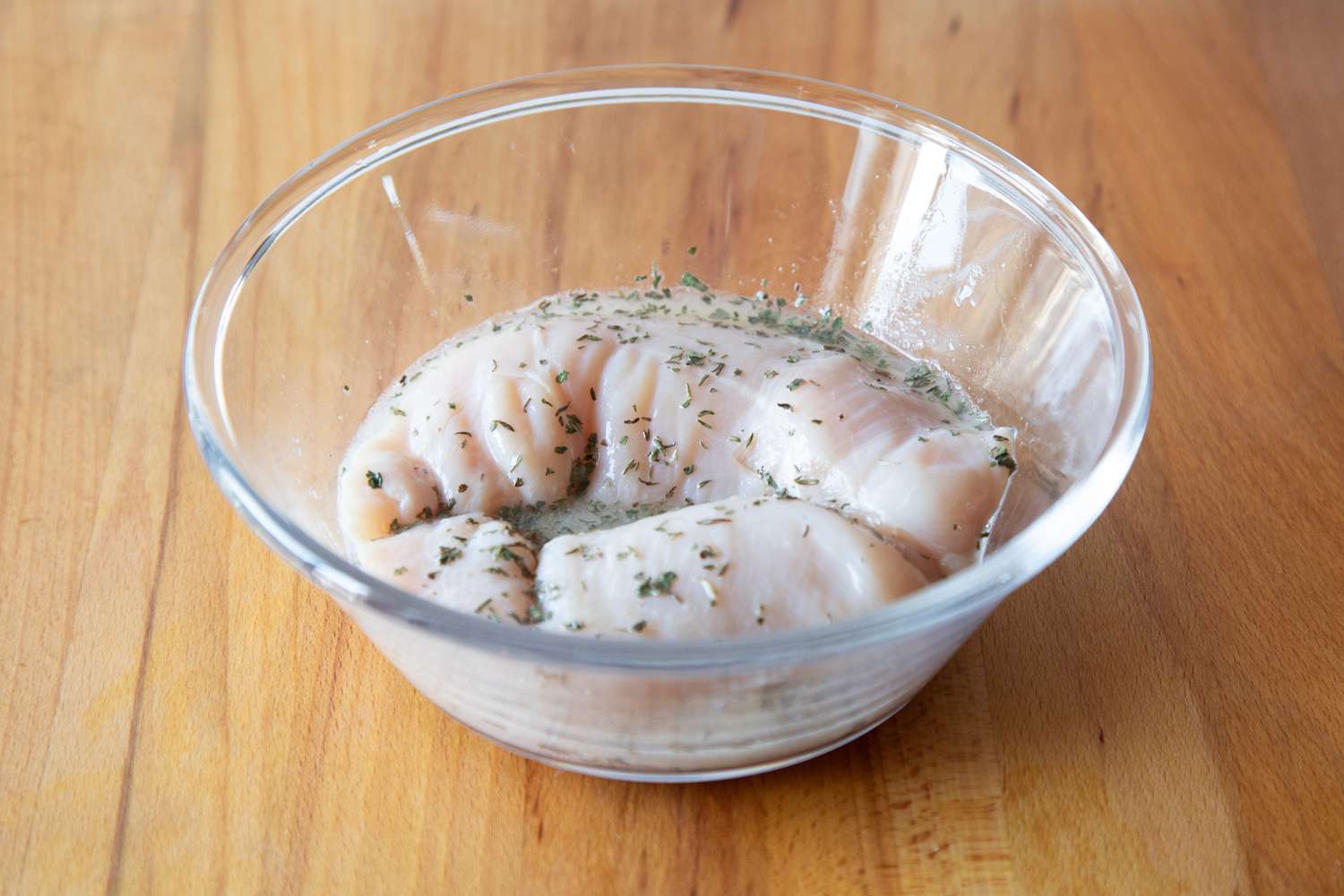 Marinating chicken in a bowl to make a poached chicken recipe.