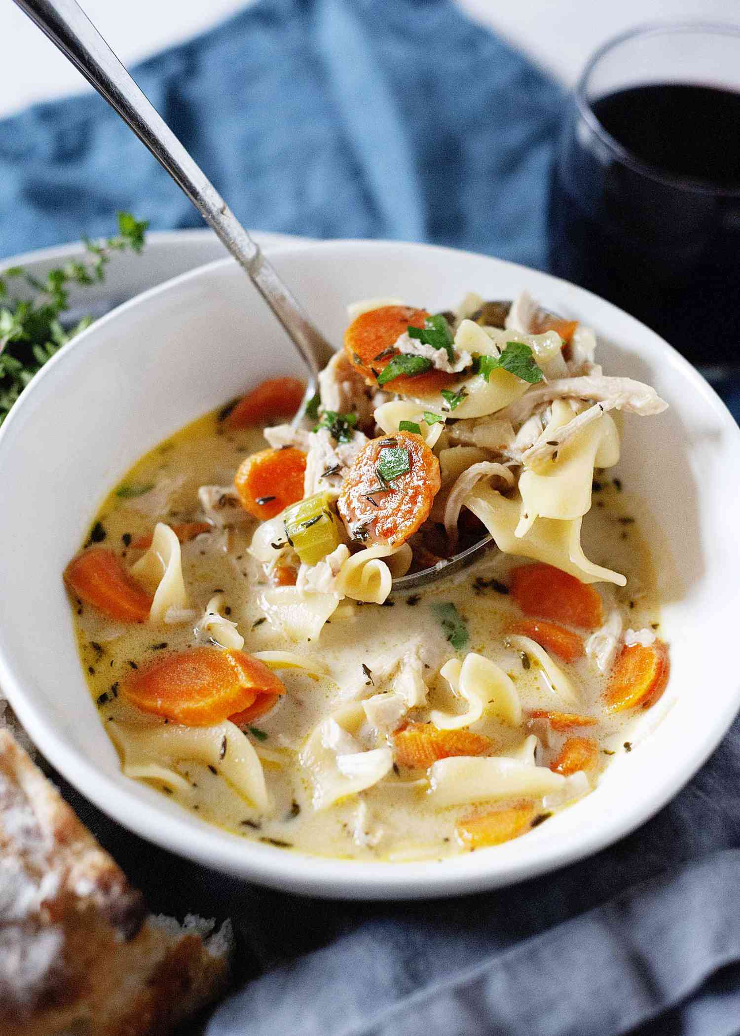 A ladle spooning chicken noodle soup into a bowl