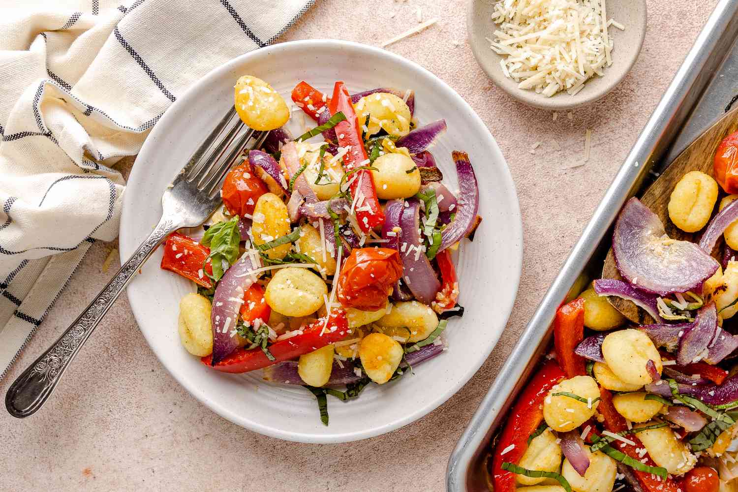 Sheet Pan Gnocchi With Zucchini, Tomatoes, and Bell Peppers on a Plate with More on a Sheet Pan