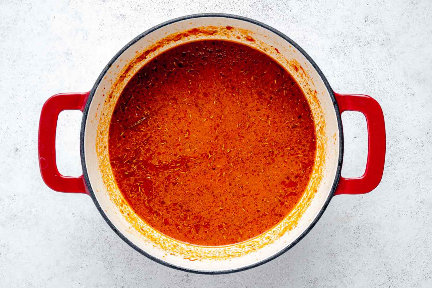 Spices and Rice Stirred into Jollof Rice Ingredients in Dutch Oven 