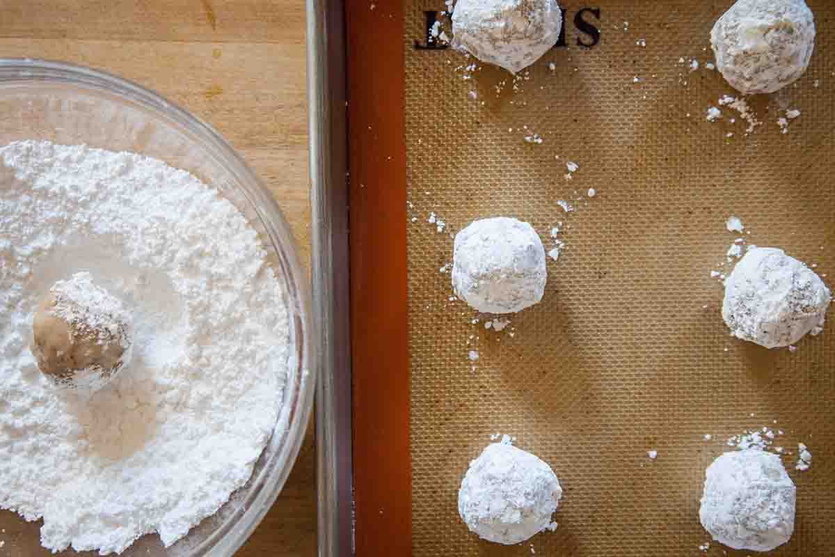 Rolling Mexican Wedding Cookies in Powdered Sugar and placing them on a Baking Sheet