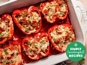 Stuffed bell peppers filled with a mixture of cooked ingredients topped with melted cheese in a baking dish labeled Simply Recipes