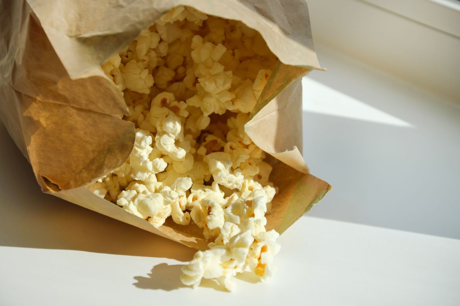 A paper bag with popcorn spilling out onto a surface