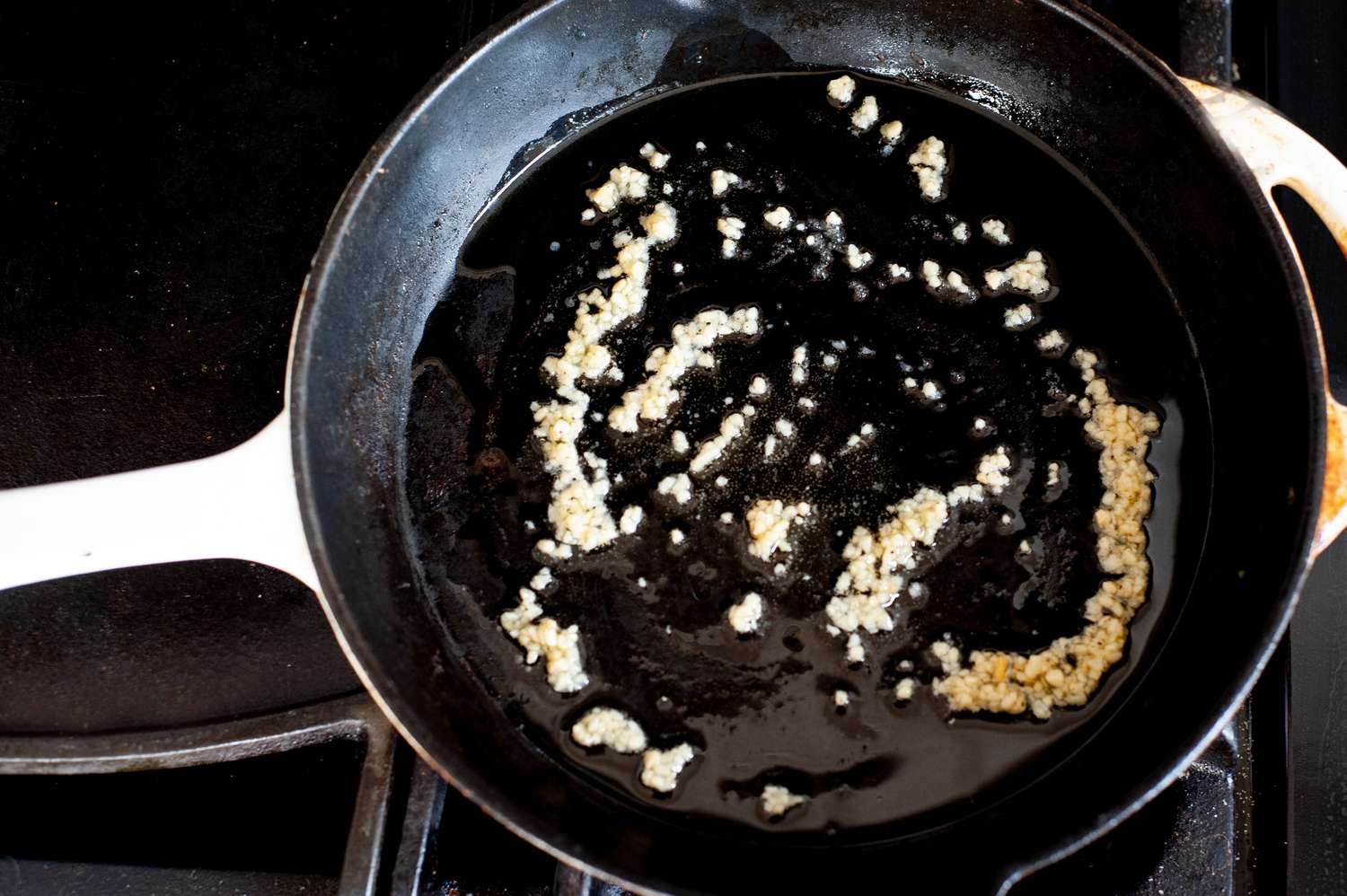 Sauteeing garlic in a skillet for a roasted cabbage steaks recipe.