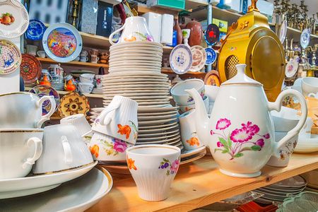 Different used vintage porcelain dishes and other home related objects in flea market second hand shop