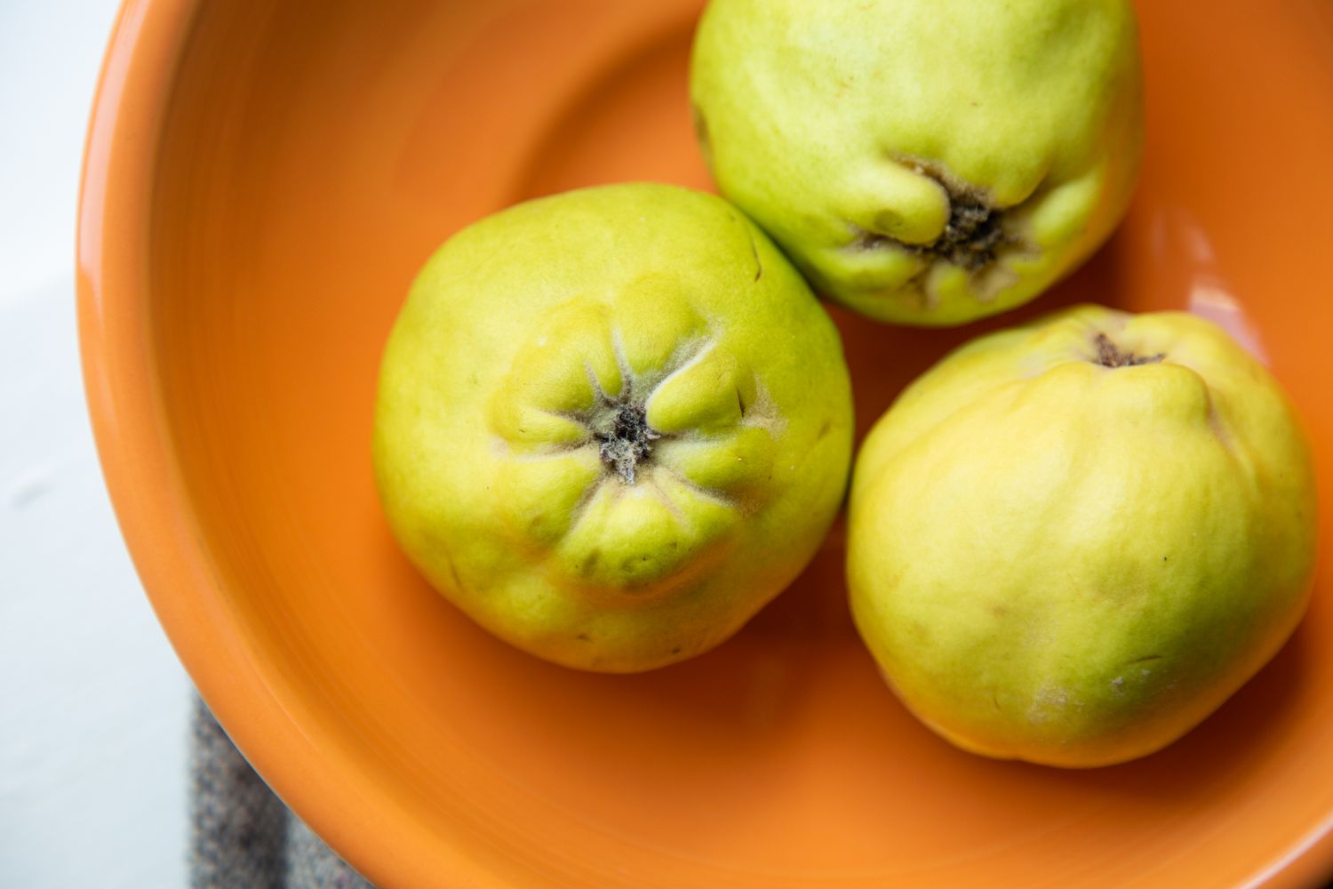 Three quince in an orange bowl