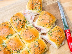Hot Ham and Cheese Sandwiches on a Cutting Board with a Knife