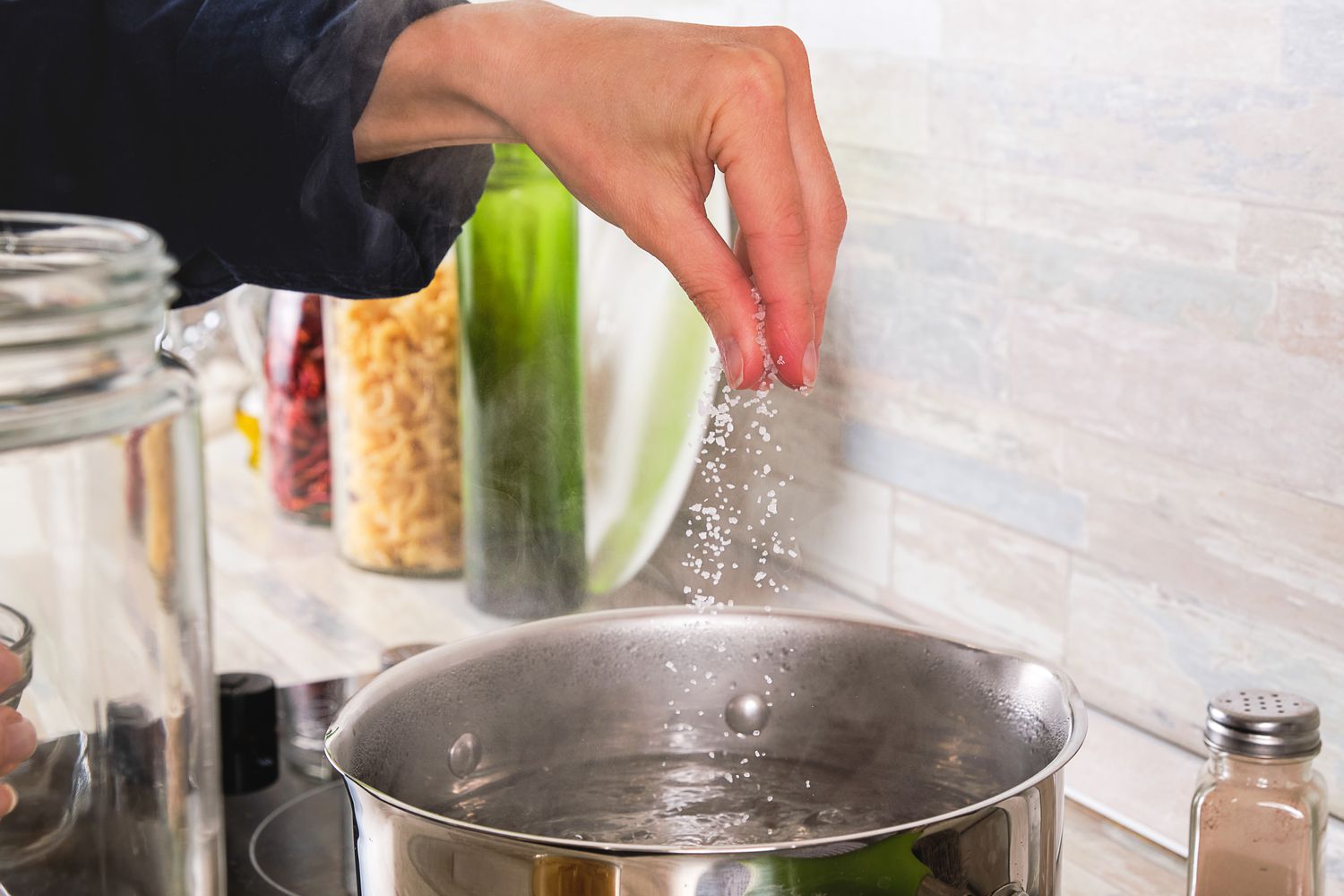 someone adding salt to a pot of water