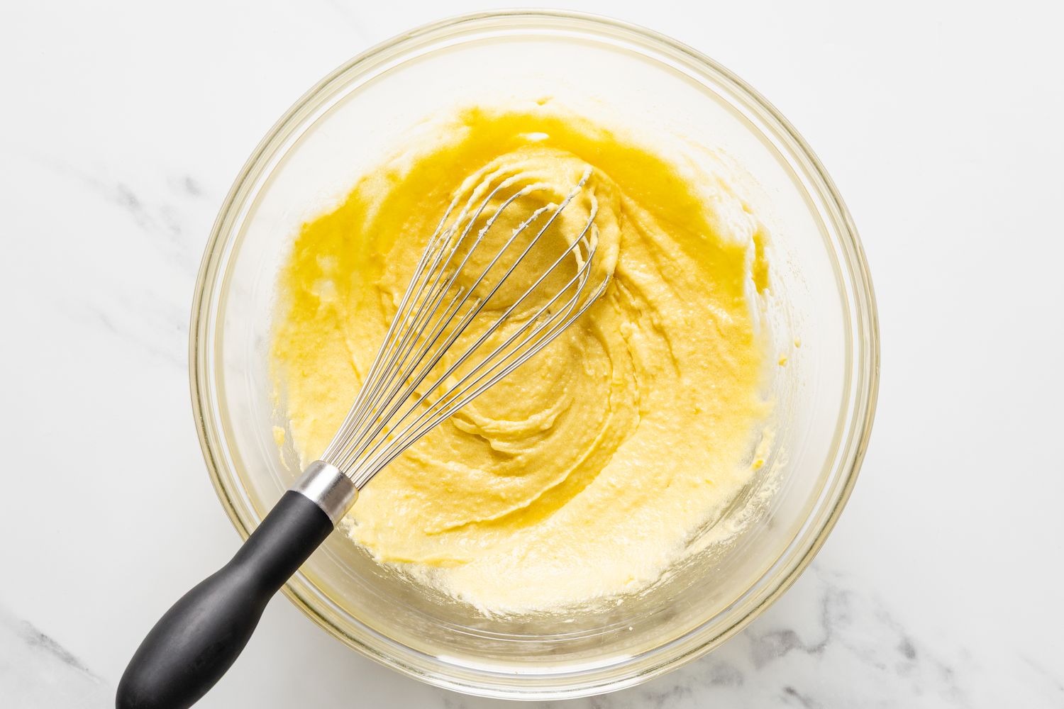 Overhead view of a whisk mixing lemon juice into the filling for Magic Lemon Pie recipe