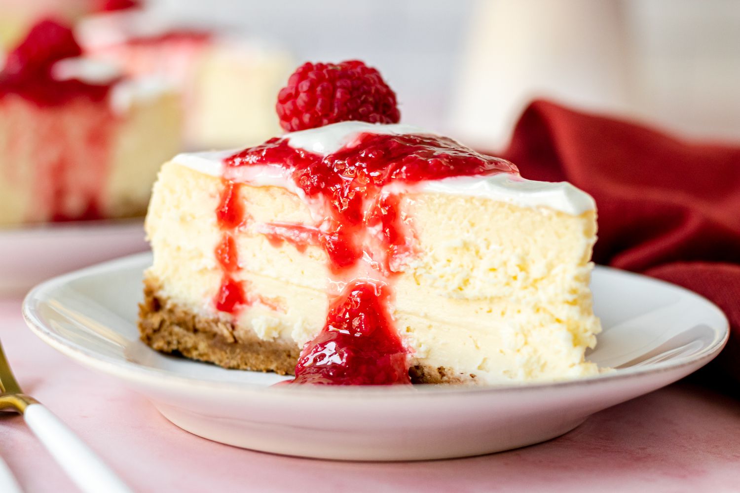 A slice of cheesecake topped with raspberry sauce.