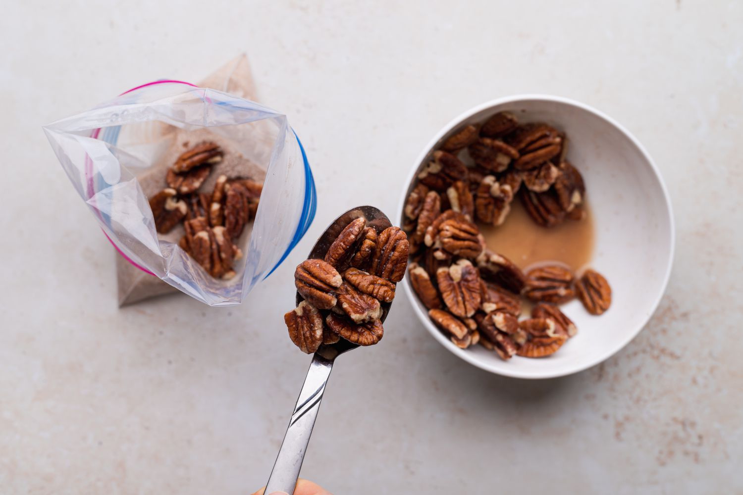Spooning coated pecans into zip top bag to show how to make candied pecans.