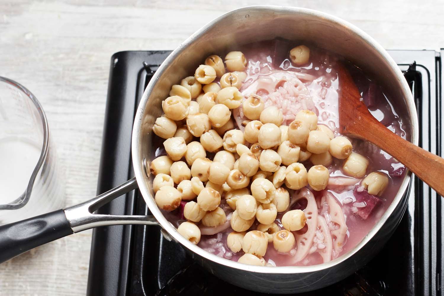 Adding lotus seeds to a pot of Vietnamese coconut rice pudding 