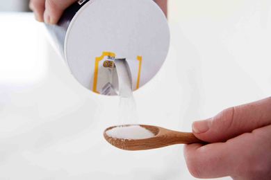 Table salt poured into small wooden spoon