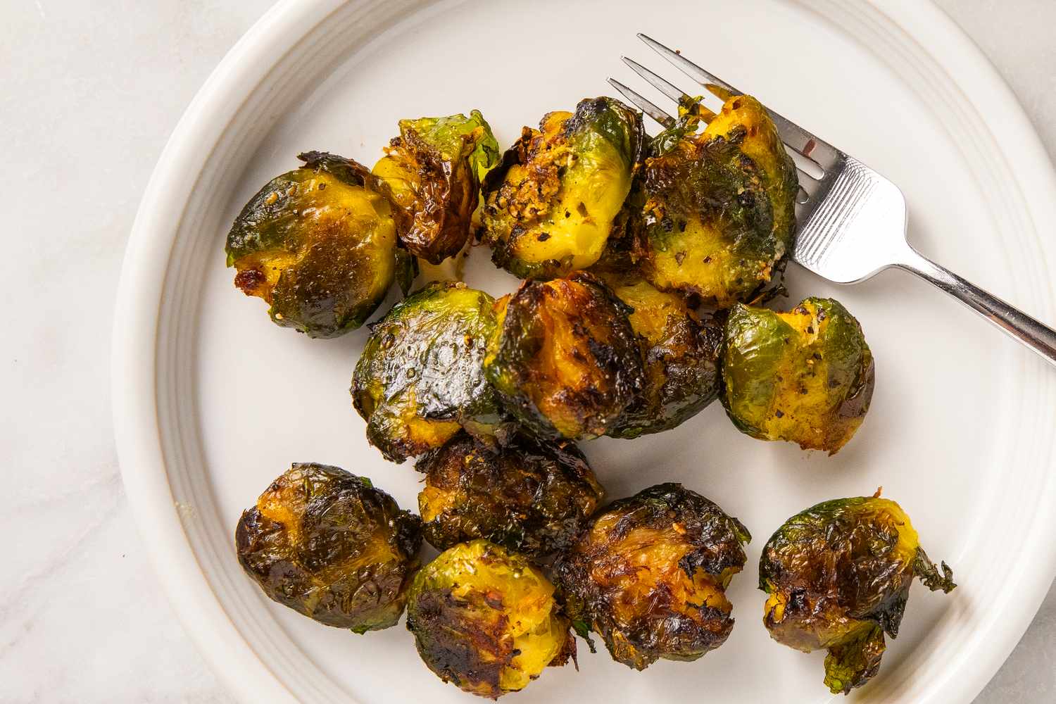 Plate of smashed Brussels sprouts on a white dish with a fork