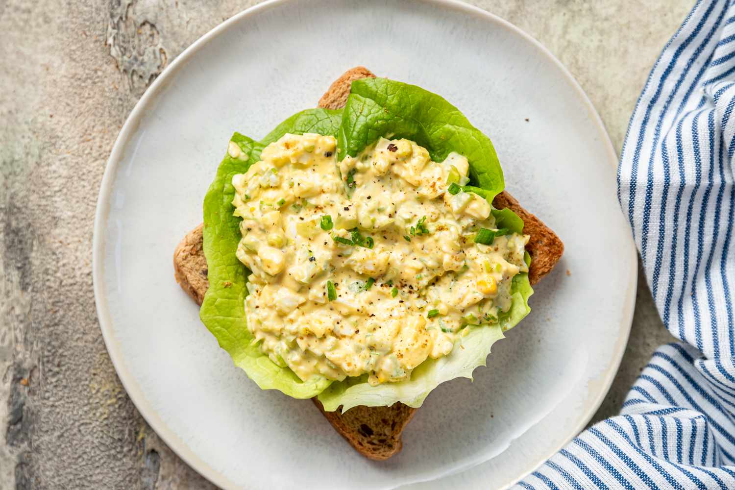 An open-faced Egg Salad Sandwich on a plate with lettuce