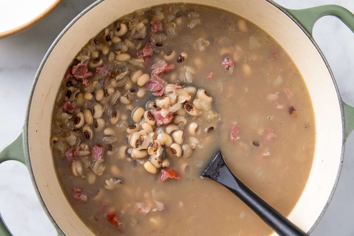 A pot of blackeyed peas stew with a black ladle