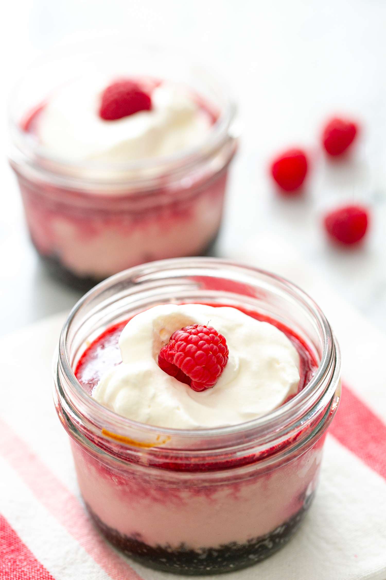 Raspberry cheesecake in a jar topped with whipped cream and fresh raspberry