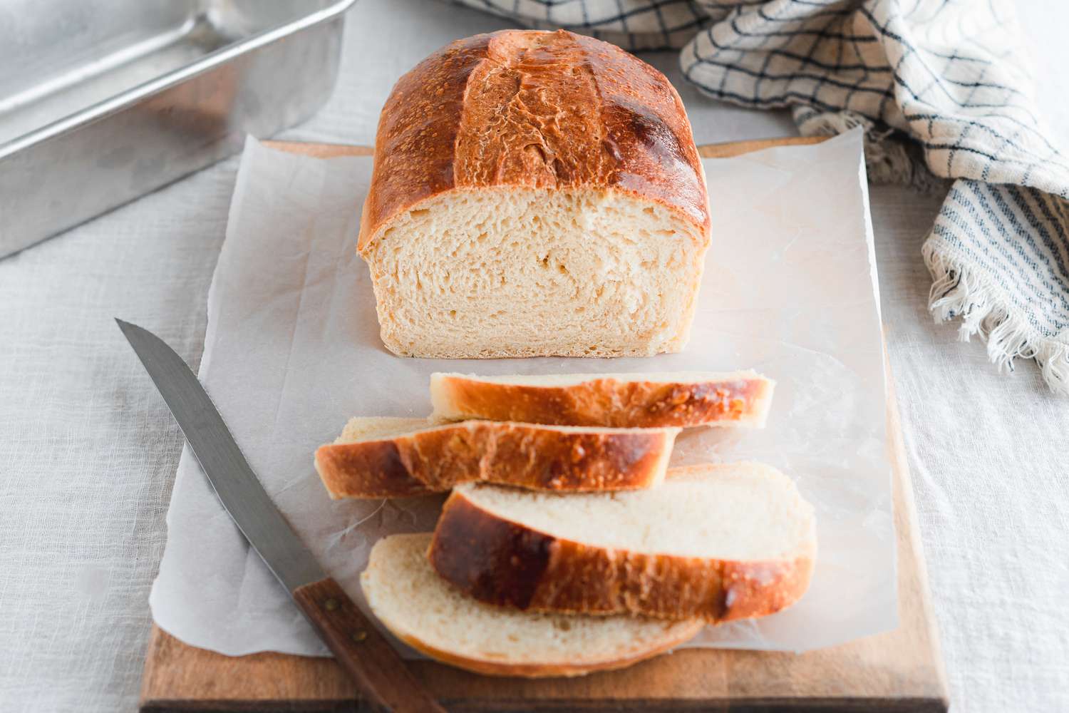 On Parchment on a Cutting Board, Slices Cut from a Sourdough Sandwich Loaf Next to the Remaining Loaf