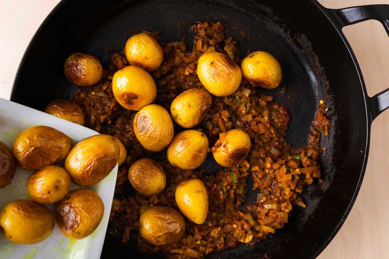 potatoes being added to the pan with other ingredients for Bombay Aloo (Bombay Potatoes)
