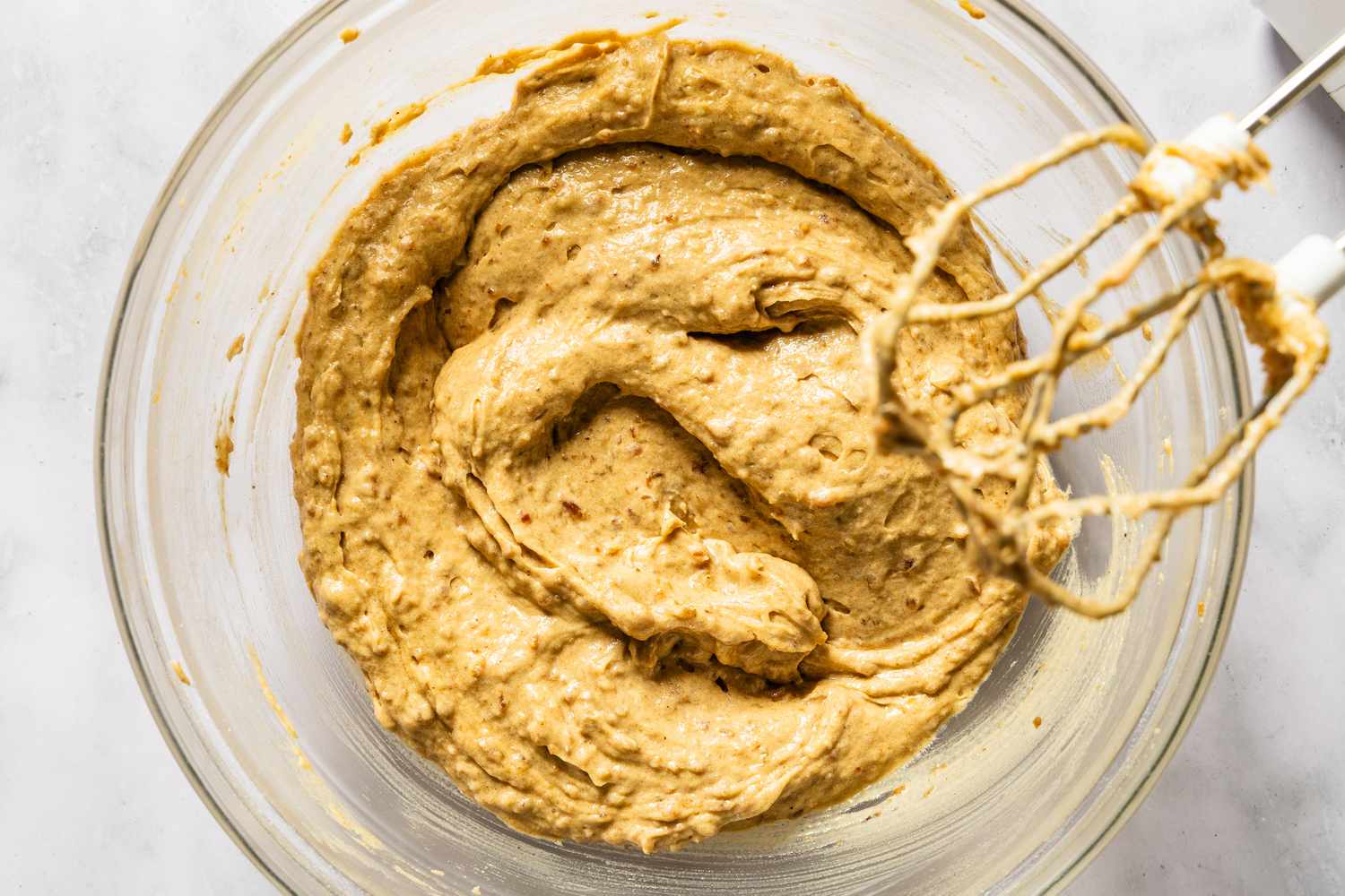 A bowl of batter being mixed with an electric mixer