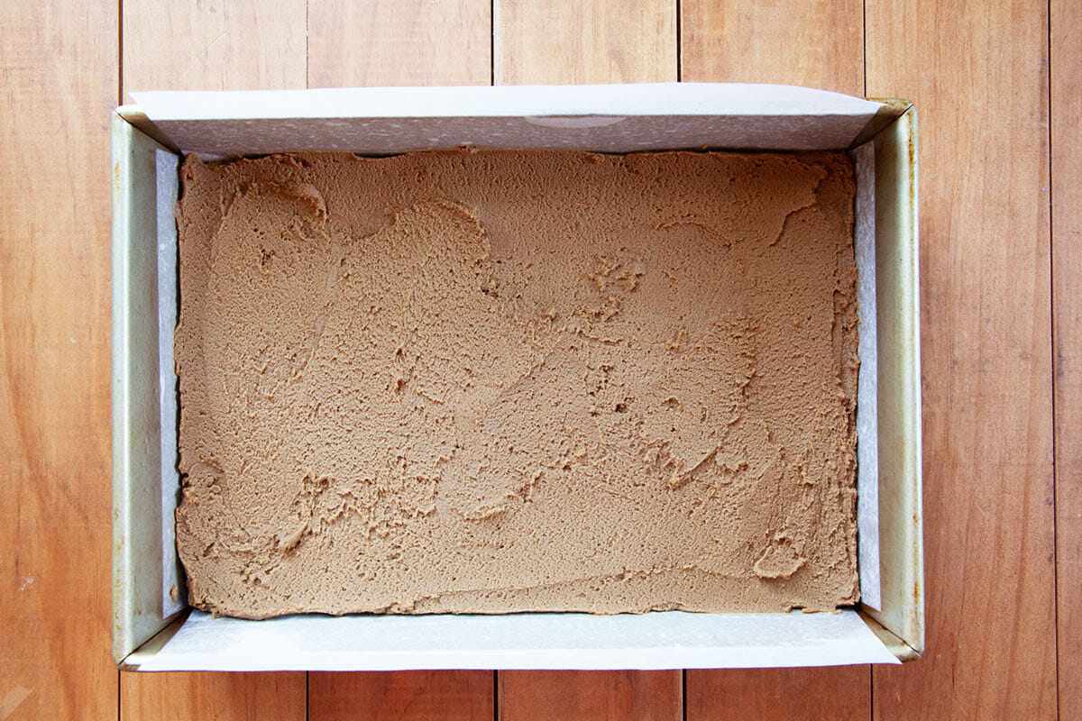 Batter spread in a parchment lined baking pan to show How to Make Gingerbread Bars.