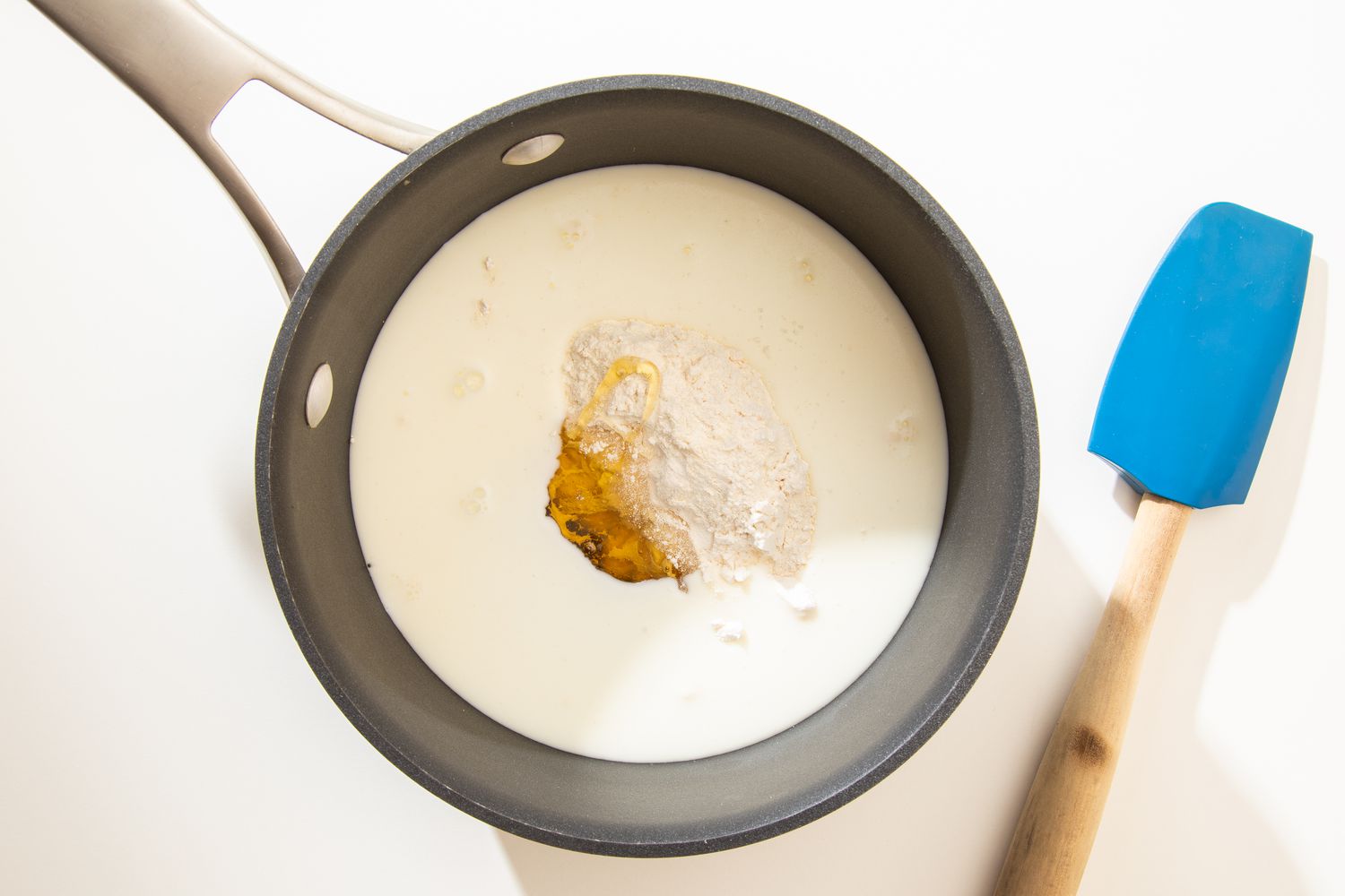 Flour, milk, and honey in a saucepan for salted honey rolls recipe
