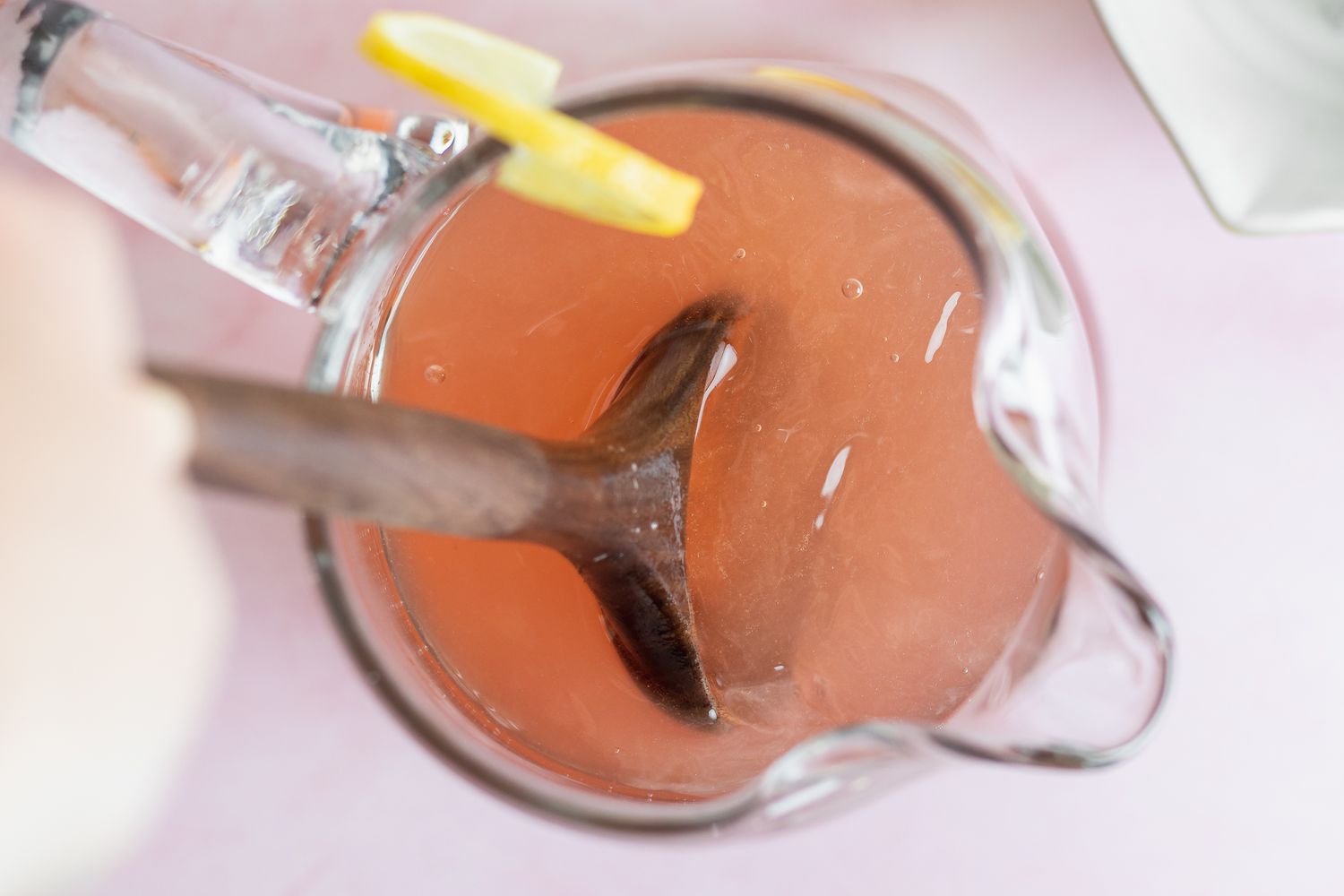 Stirring a pitcher to show how to make pink lemonade.