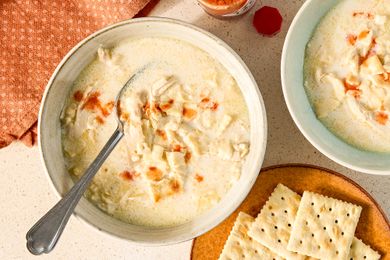 Bowls of creamy chicken mull soup with a spoon served with crackers