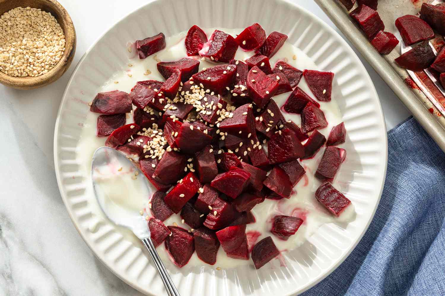 Overhead shot of a plate with chopped pieces of beets over a creamy sauce, topped with sesame seedsOverhead shot of a plate with chopped pieces of beets in a creamy sauce, topped with sesame seeds