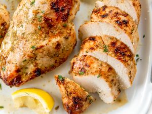 Cooked chicken breasts with a lemon wedge on a white plate