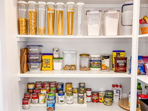 A neatly organized pantry with jars of pasta containers of grains canned goods and various other food items arranged on shelves