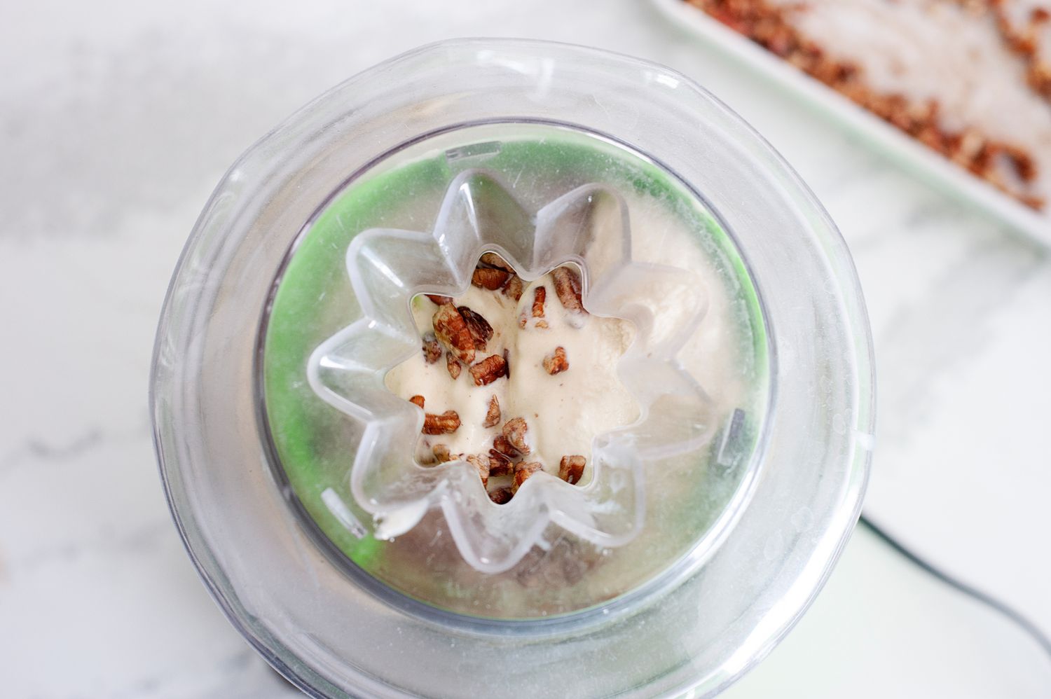 Adding pecans to the churned ice cream to make butter pecan ice cream.