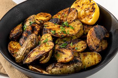 Grilled Fingerling Potatoes and a Grilled Halved Lemon in a Black Bowl 