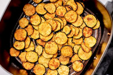 Air fried zucchini slices in the basket of an air fryer