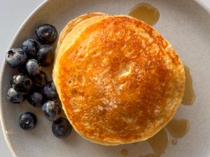 A plate with pancakes blueberries and syrup