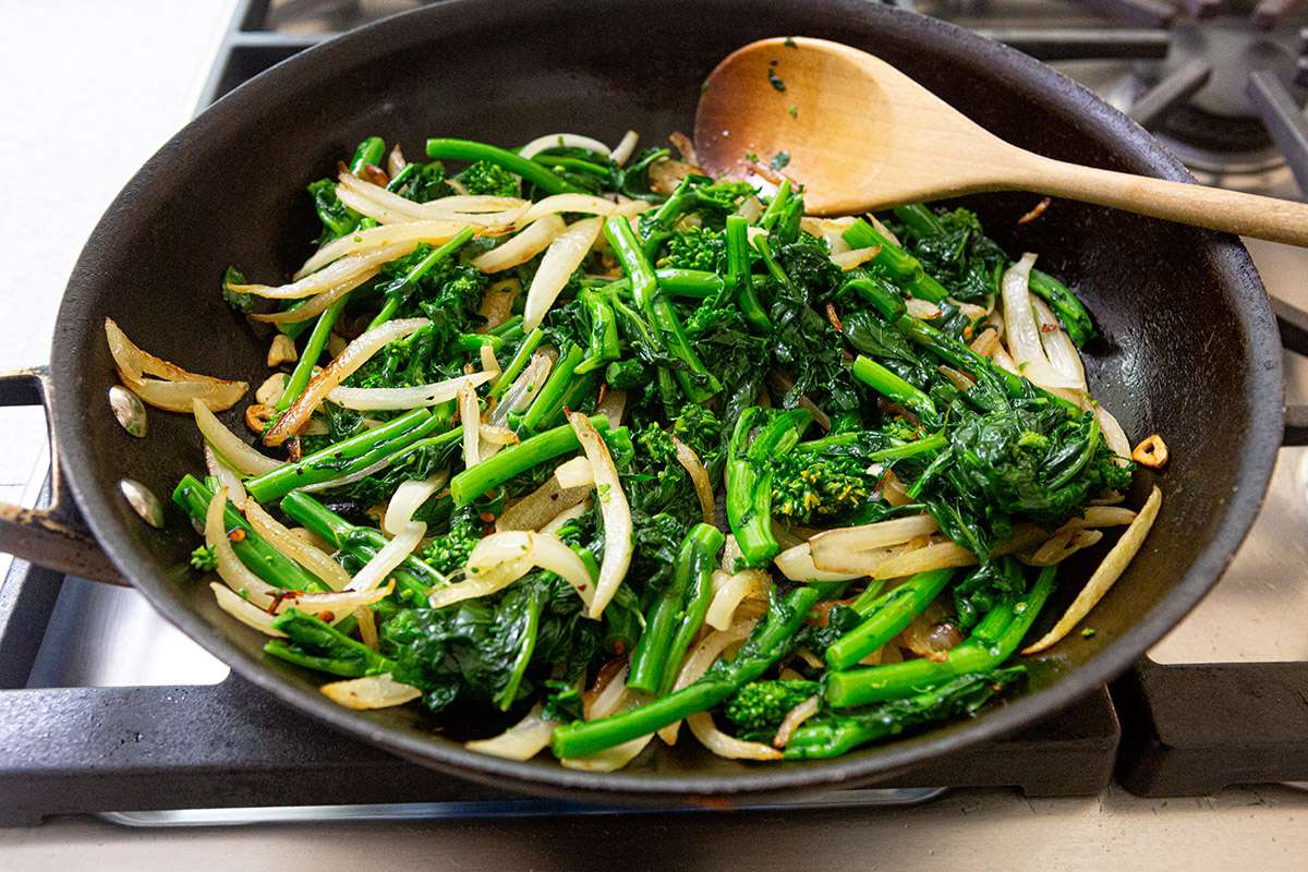 Onions and broccoli rob cooked in a skillet.