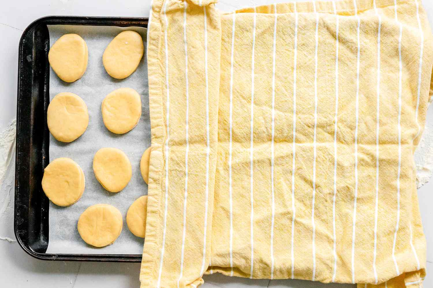 Sufganiyot (Israeli Jelly Donuts) on Lined Baking Sheet Covered with a Kitchen Towel for Second Proofing