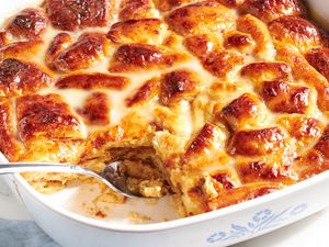 Bread pudding with cinnamon rolls in a baking dish partially served with a spoon