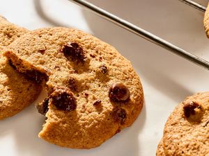 Chocolate chip cookies on a baking rack one with a bite taken out of it