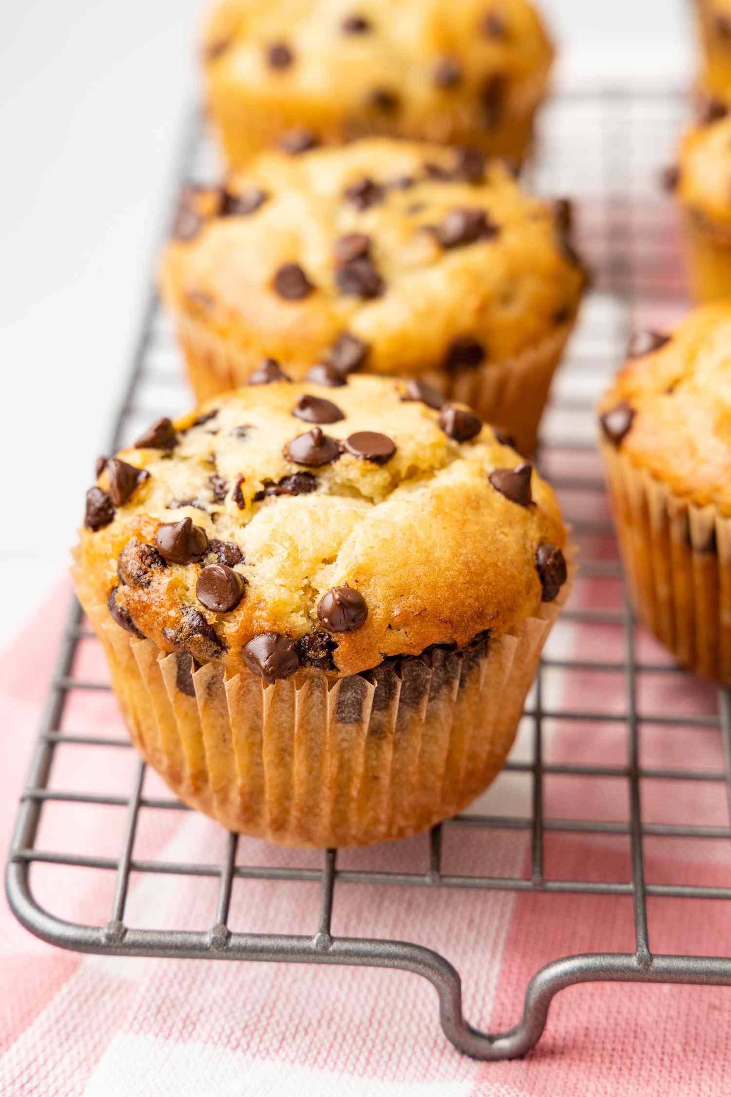 Banana Chocolate Chip Muffins on a Cooling Rack Over a Kitchen Towel