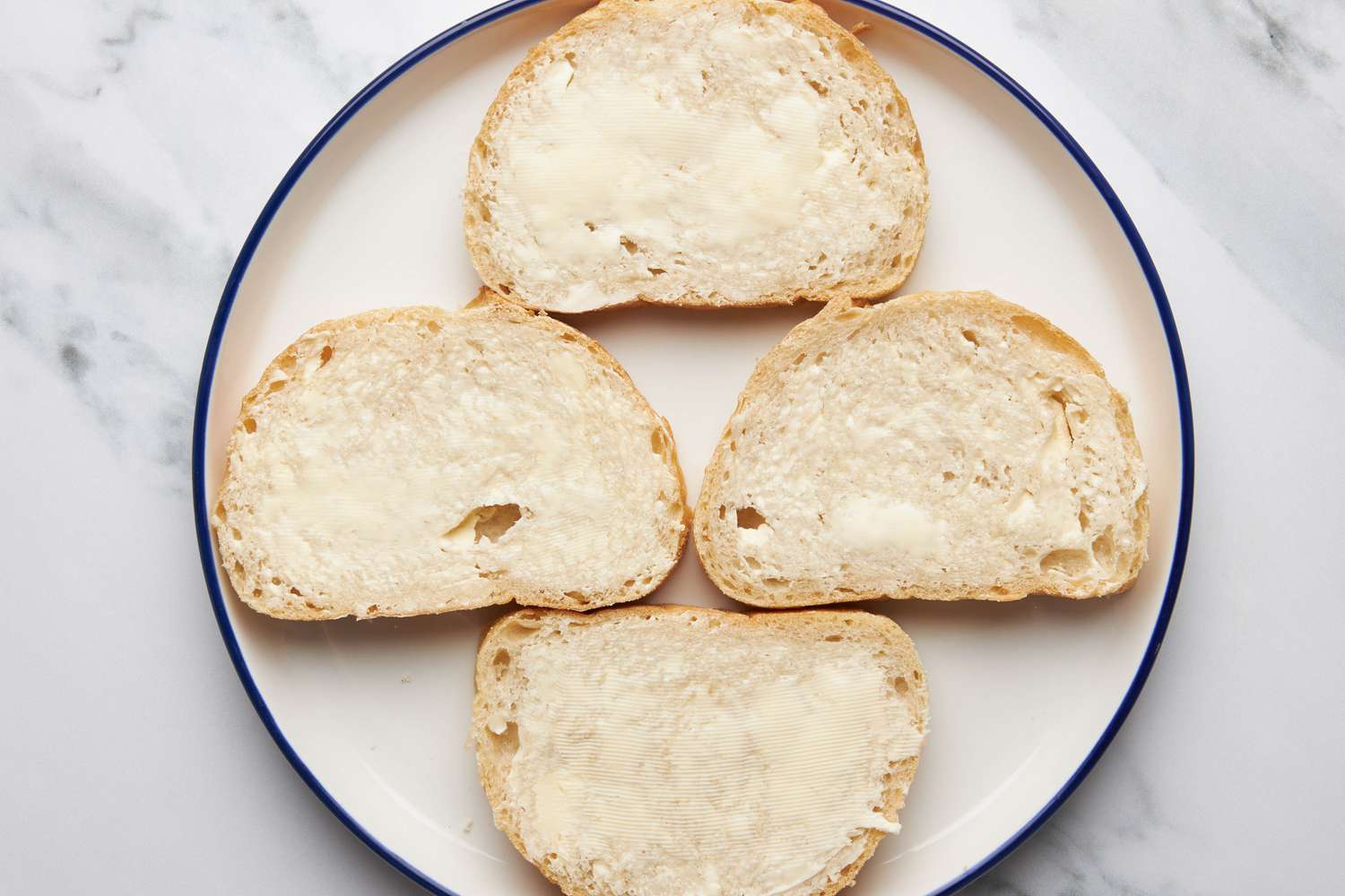 Assemble the sandwich: Buttered sourdough slices (four) on a plate for jalapeÃ±o popper grilled cheese recipe