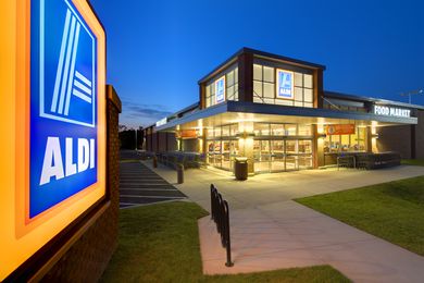 Exterior view of an Aldi grocery store at dusk with lit signage and parking area
