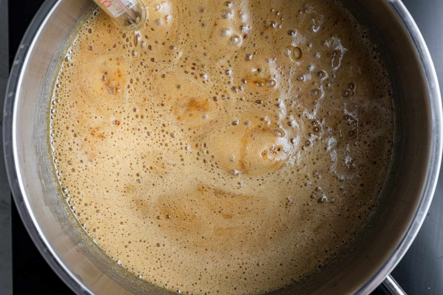 Simmering caramel to make a pecan praline recipe.