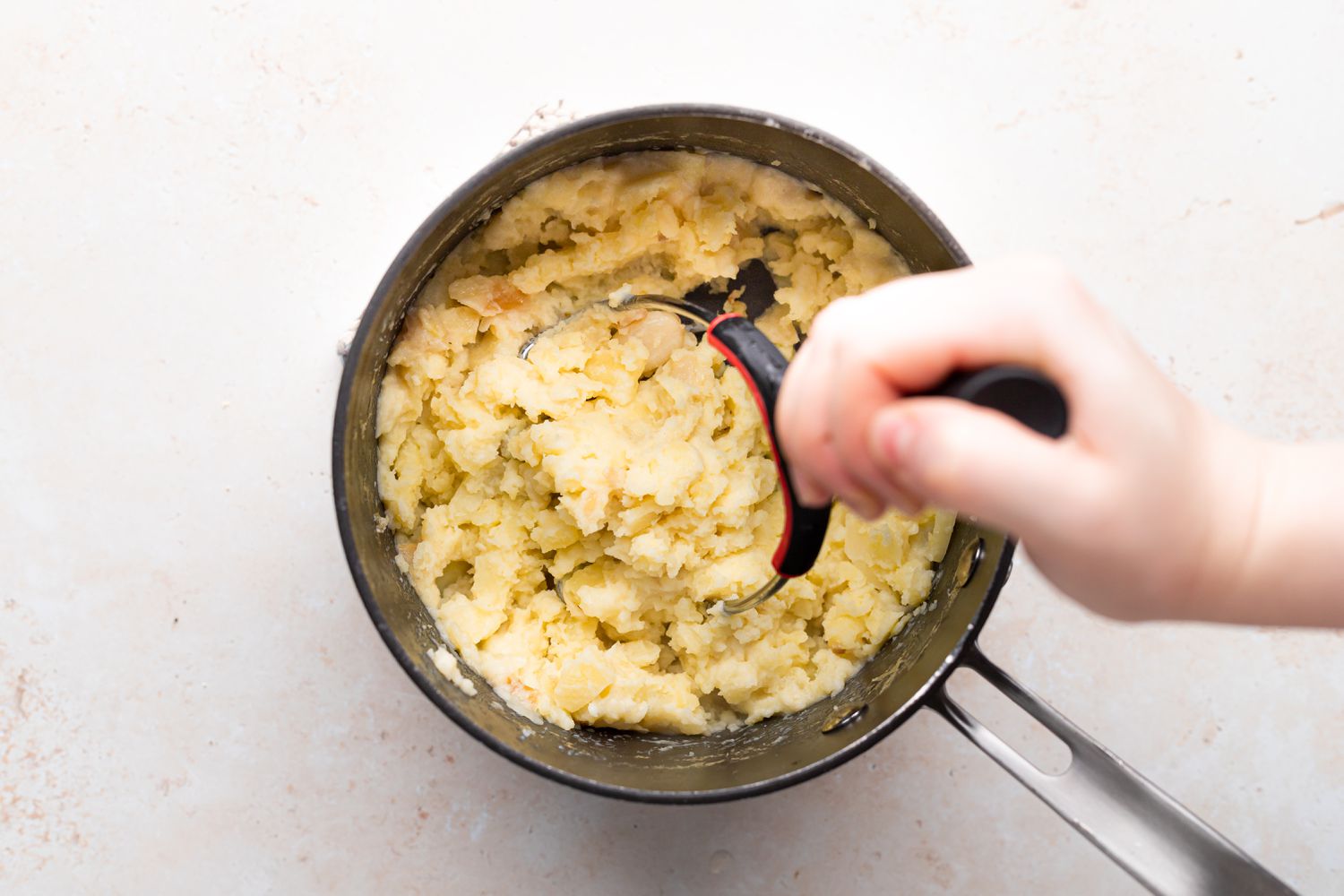 Mashing potatoes in a pot for a garlic mashed potatoes recipe.