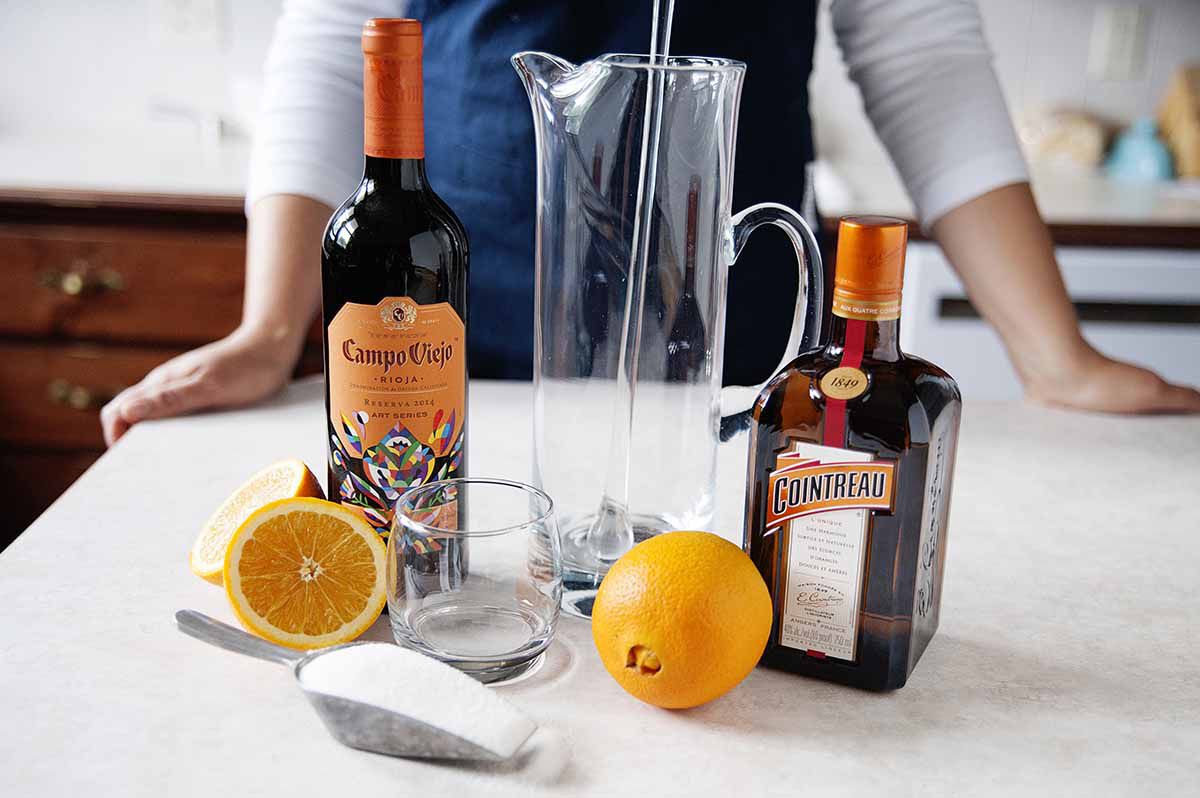 Homemade Sangria Recipe - orange slices in a pitcher of sangria on a silver tray with two poured glasses of sangria