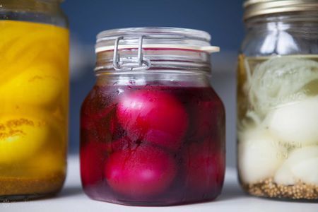 Three jars of pickled eggs; the middle jar includes pickle juice for bright pink eggs