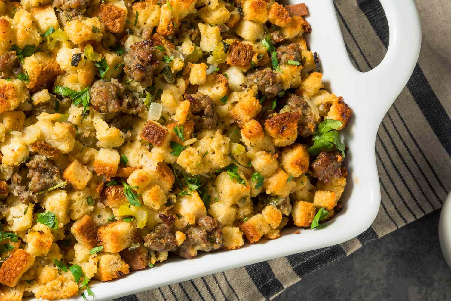 Overhead view of the corner of a white casserole dish of pork sage stuffing
