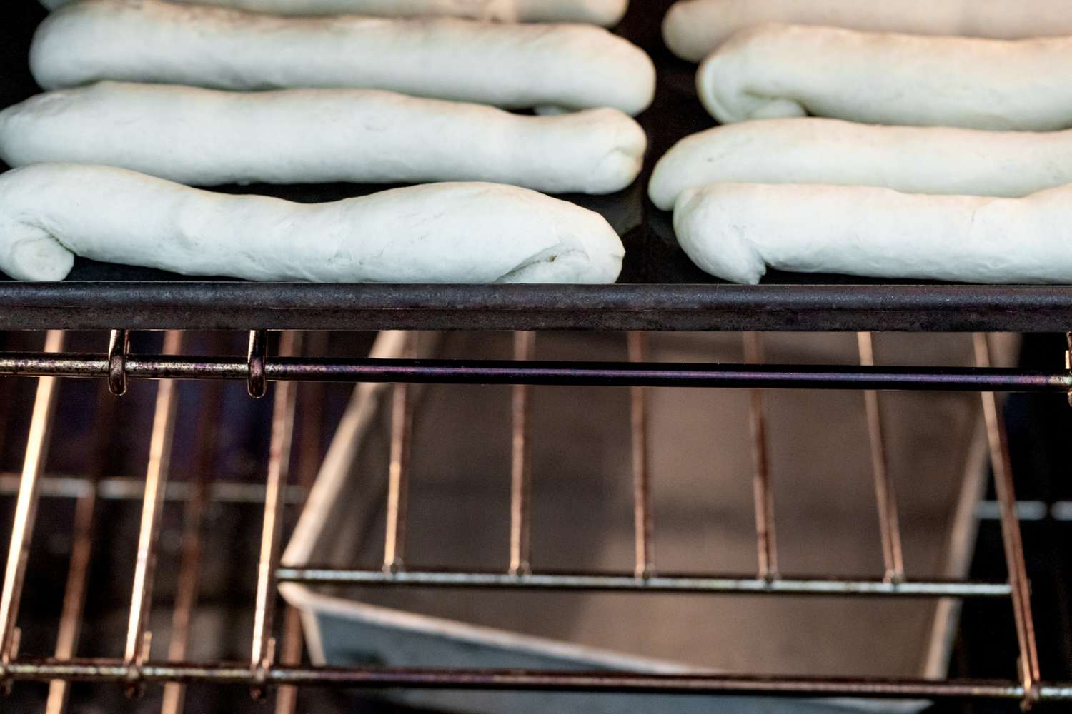 Breadsticks Baking in Oven with a Pan of Water on Shelf Below Baking Pan